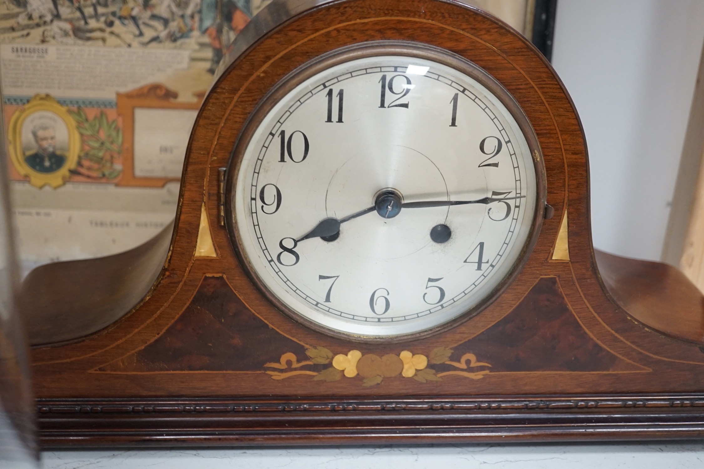 An early 20th century inlaid mahogany mantel clock, a skeleton clock under glass dome, a brass desk calendar and a 19th century French framed print, skeleton clock and dome 32cms high